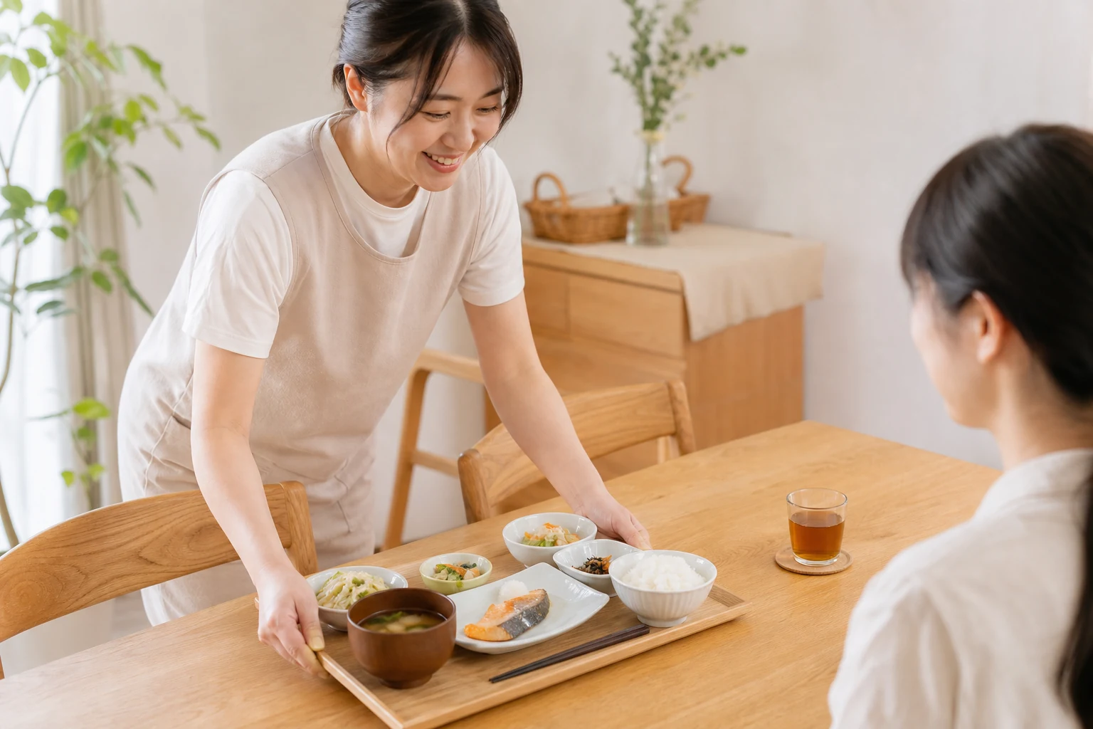 女性スタッフが食卓に手作りごはんを配膳する様子
